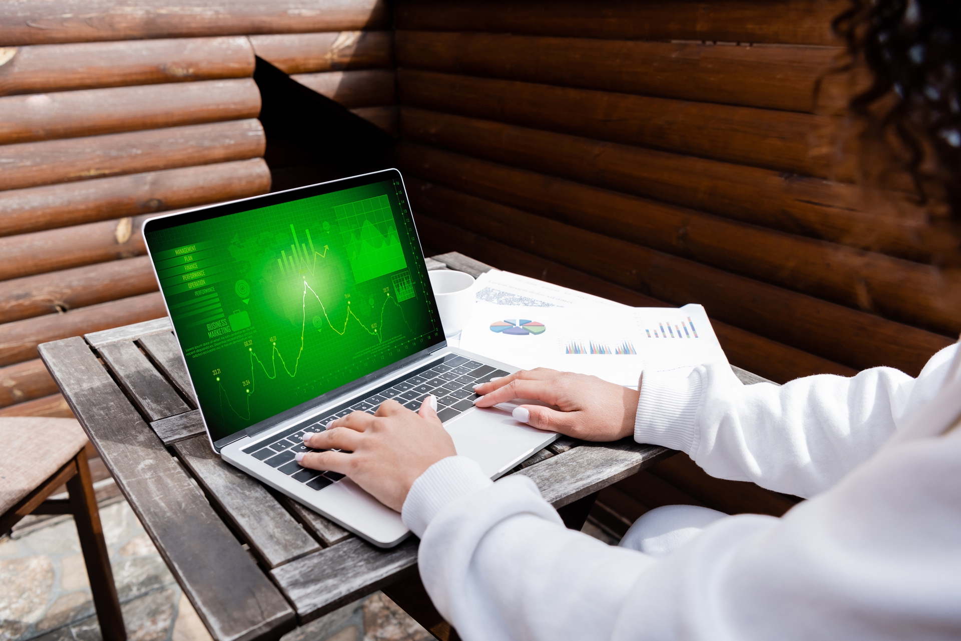woman at table outside working with a laptop with a green digital display
